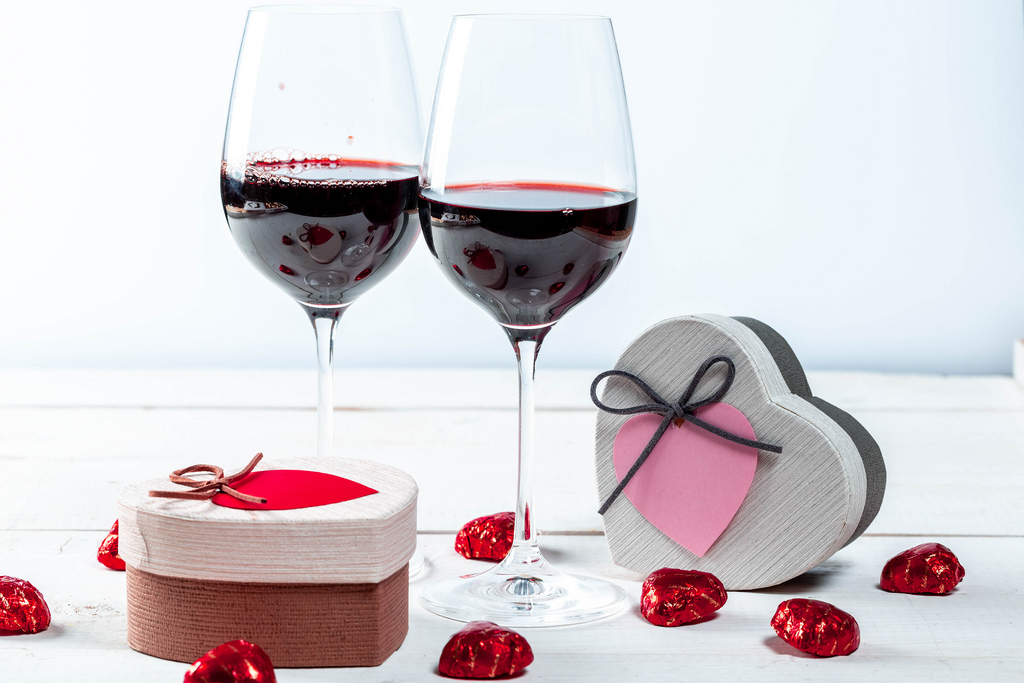 Glasses of red wine with gifts and chocolates