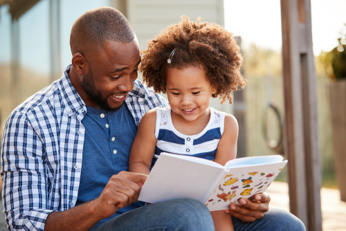 Young,Black,Father,And,Daughter,Reading,Book,Outside