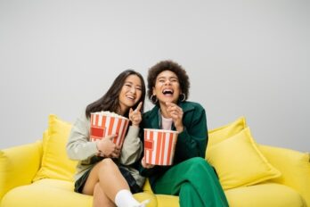 Cheerful,Asian,Woman,With,Popcorn,Pointing,With,Finger,While,Watching