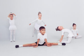 Little,Ballerinas,Girls,And,Boy,Doing,Splits,On,White,Floor,