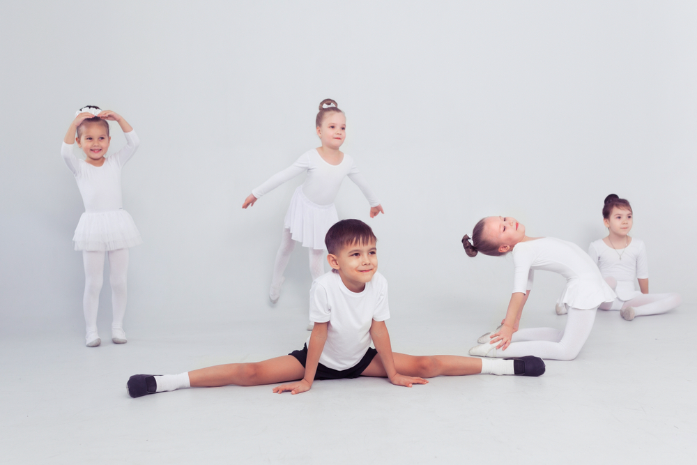 Little,Ballerinas,Girls,And,Boy,Doing,Splits,On,White,Floor,