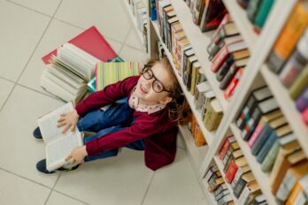 Girl,With,Glasses,Reads,A,Book,Sitting,On,The,Floor