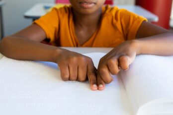 Focused,Biracial,Schoolboy,Reading,Braille,With,Hands,In,Classroom.,Disability,